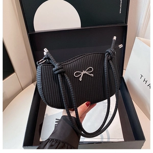 Detail shot of the black woven texture and silver metal bow on this women's shoulder bag