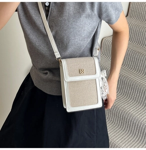 Detail of white canvas crossbody bag with gold floral buckle and delicate lace ribbon