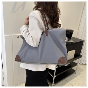 Modelo con un gran bolso de viaje gris con asas de cuero marrón en una habitación moderna