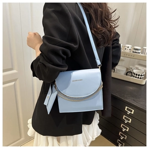 Détail du sac à bandoulière bleu avec chaîne en métal et petit porte-monnaie triangle