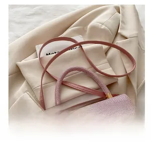 Dettaglio della borsa rosa a trama intrecciata con fibbie dorate e tracolla in pelle