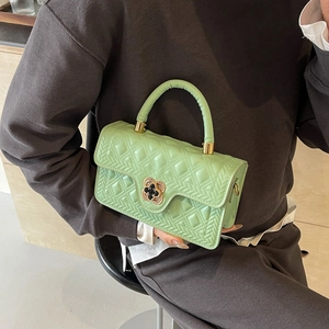 Detail of mint green quilted leather handbag with floral gold lock and textured pattern