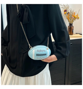 Close-up of a blue rugby-shaped crossbody bag with gold chain strap on a model