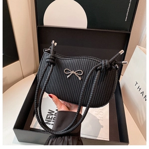 Detail of black woven shoulder bag with silver bow accent in elegant gift box