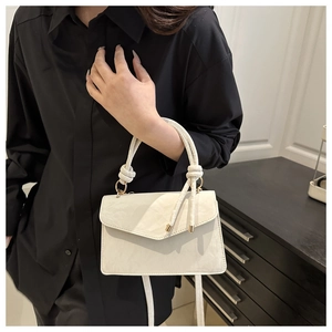 Detail of cream flap handbag with unique knotted handle and slim crossbody strap