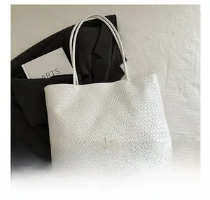 Close-up of white woven tote bag with Fashion label and sleek shoulder straps