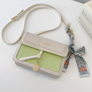 Detail of color-block crossbody bag featuring silk scarf handle and gold brand lettering