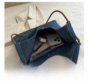 Macro detail of spacious interior in denim tote bag holding tablet and accessories