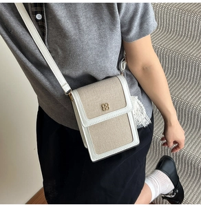 Chic off-white woven canvas crossbody bag with leather trim and gold clover buckle detail