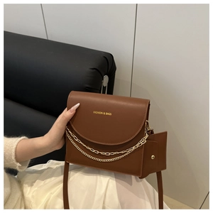Détail du sac en similicuir marron avec chaîne dorée, logo et mini porte-monnaie