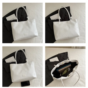 Close-up of white woven leather tote bag featuring a magnetic clasp and interior lining