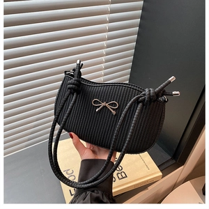 Detail of black woven shoulder bag featuring a silver metal bow and knotted strap design