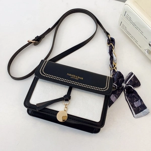 Detail of contrast stitch handbag with gold hardware and stylish printed silk scarf decoration