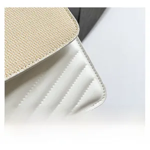 Detail of woven straw flap and white faux leather body with V-shaped chevron stitching