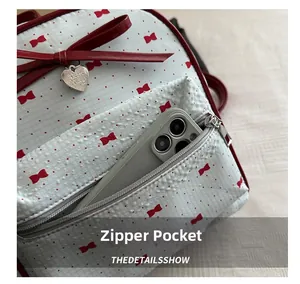 Close-up of front zipper pocket on white backpack with red bow and polka dot patterns