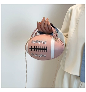 Detail of pink rugby-shaped handbag with gold chain strap and letter embossing