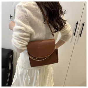 Détail d'un sac bandoulière en cuir marron avec décoration de chaîne sur un mannequin