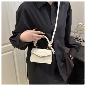 Detailed view of cream mini flap crossbody bag with knotted handle and metal hardware