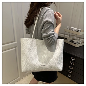 Detail of white woven texture tote bag with thin straps and a small Fashion label