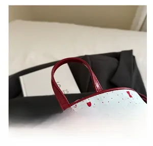 Detail of red patent leather handle and bow pattern on a stylish ladies backpack