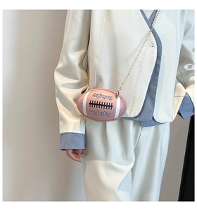 Pink rugby-shaped crossbody bag with golden chain strap on a white suit model