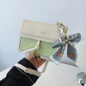 Detail of avocado green and cream crossbody bag with textured faux leather and silk scarf handle