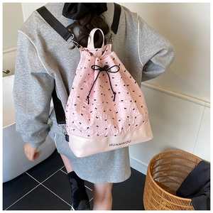 Detailed close-up of pink drawstring backpack with black bow print and pleated texture