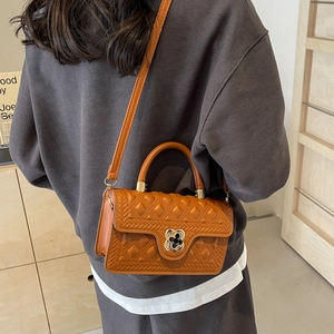 Detail of caramel quilted handbag featuring flower buckle and detachable shoulder strap
