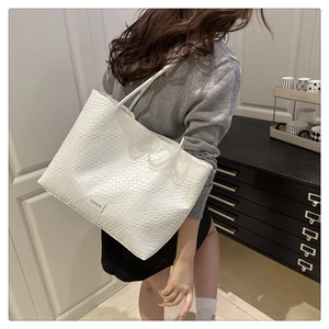 Detailed view of beige tote bag with woven texture and Fashion label worn on shoulder