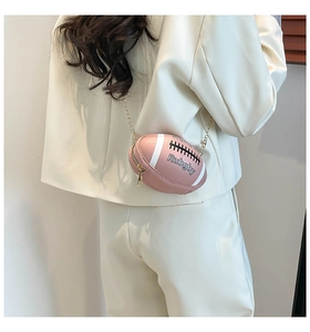 Detail view of pink rugby-shaped crossbody bag with gold chain strap on white blazer