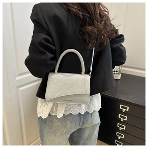 Dettaglio di una borsa a mano scintillante in paillettes argento con manico rotondo