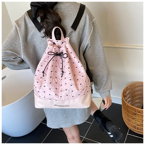Detail of pink drawstring backpack with black bow prints and logo leather base