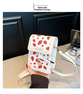Detail of white strawberry print crossbody bag with metal charm and adjustable strap