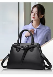 Detail of black lychee grain leather handbag with buckle decor and adjustable shoulder strap
