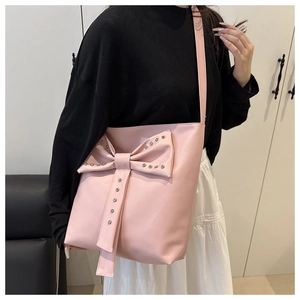 Detailed view of pink tote bag with large bow, metallic studs and slim shoulder strap