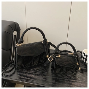 Detail of black pleated tote bags in two sizes with gold clasps and knotted handles