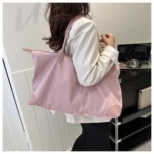 Bolso de viaje grande de nailon rosa llevado al hombro en una oficina moderna