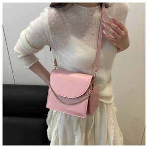 Détail d'un sac bandoulière rose avec chaîne dorée et mini pochette sur mannequin