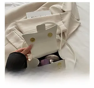 Detail showing white mini bag interior with makeup items and double magnetic closure