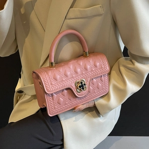 Detail of pink quilted handbag with gold flower lock and textured rhombic stitching