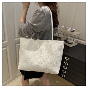 Detail shot of white woven texture tote bag featuring a Fashion label for work