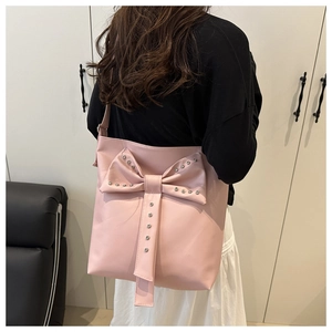 Close-up of pink bow trim and rivet details on stylish PU leather tote bag