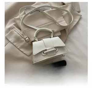 Size comparison of white textured leather handbag next to a smartphone on a beige blazer