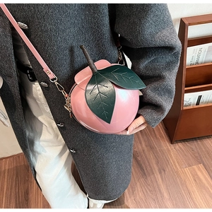 Vue détaillée du sac bandoulière créatif en forme de pêche rose avec feuilles vertes
