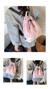 Detail of pink quilted drawstring backpack with embroidered bows and leather base