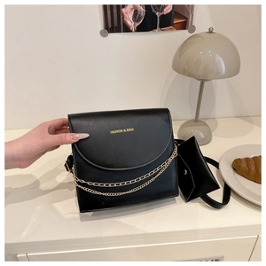Détail du sac bandoulière en similicuir noir avec chaîne dorée et mini porte-monnaie