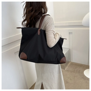 Modelo con un gran bolso de viaje negro con asas marrones en una habitación mínima