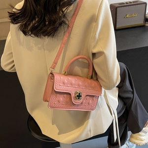 Detailed shot of pink quilted crossbody bag with clover buckle worn on shoulder