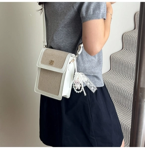 Detail of mini square crossbody bag with clover ornament and pearl lace bow accessory