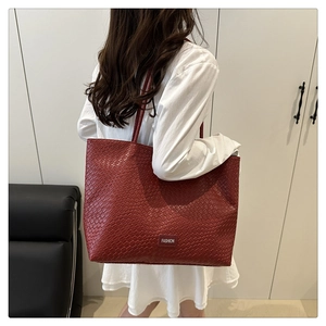 Detail view of burgundy woven leather tote bag shown on a model for casual commuting